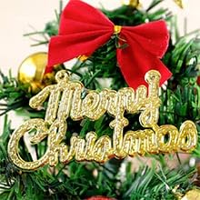 Close-up of Christmas tree branch with red bow and gold 'Merry Christmas' ornament, surrounded by twinkling lights.